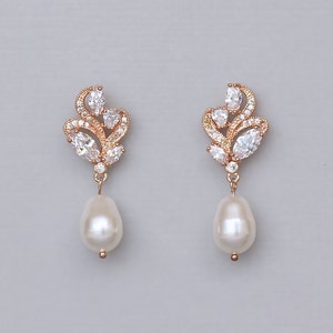 May include: Rose gold earrings with a pearl drop and a cluster of clear cubic zirconia stones in a floral design.