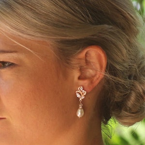May include: Rose gold earrings with a pearl drop and a delicate floral design.