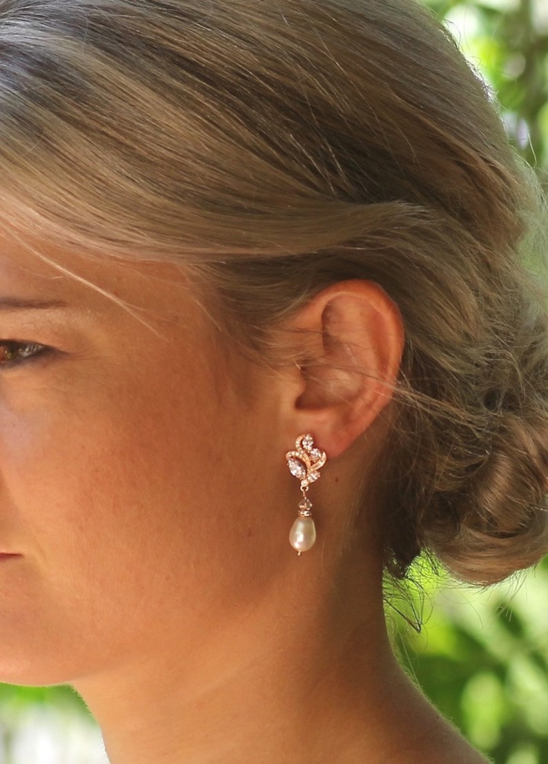 May include: Rose gold earrings with a pearl drop and a delicate floral design.