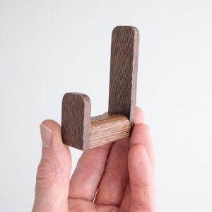 May include: A wooden wall hook with a dark brown stain. The hook is shaped like a letter J and has a rounded top.