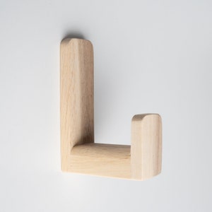 May include: A wooden wall hook with a simple L-shape design. The hook is made of light-colored wood and has a smooth, polished finish.