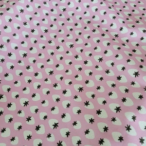 May include: Pink fabric with a repeating pattern of white strawberries and black five-pointed stars.