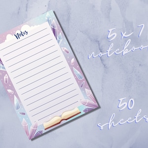 May include: A 5x7 inch notebook with a crystal and book design. The cover is purple, blue, and white with a cloud and the word "Notes". The notebook has 50 sheets.
