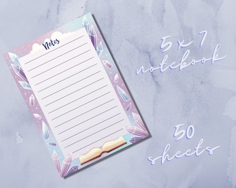 May include: A 5x7 inch notebook with a crystal and book design. The cover is purple, blue, and white with a cloud and the word "Notes". The notebook has 50 sheets.