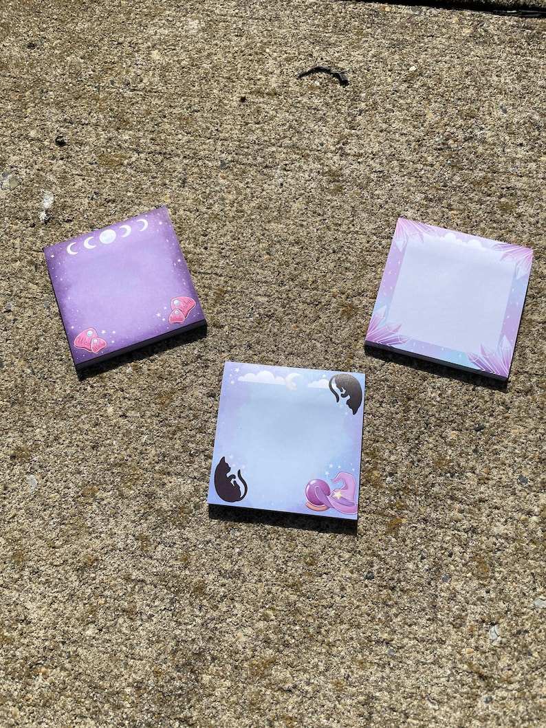 Three colorful sticky notes are lying on a concrete surface.