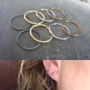 May include: A set of six hoop earrings in various sizes and finishes, including silver, gold, and black. The hoops are stacked on top of each other, creating a layered effect.