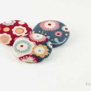 Puede incluir: Tres botones cubiertos de tela con motivos florales. Los botones son rojos, azules y blancos con una variedad de dise&ntilde;os florales.