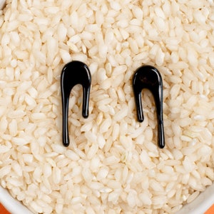 Puede incluir: Un bol blanco lleno de arroz cocido con dos formas abstractas negras en la parte superior.