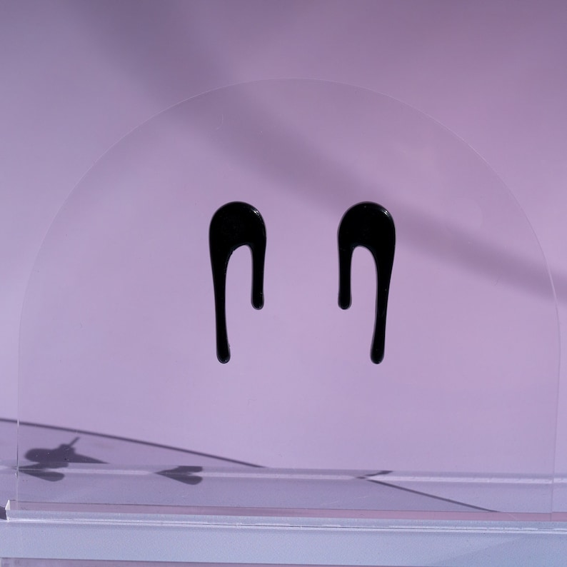 Puede incluir: Un par de pendientes de gota negros. Los pendientes est&aacute;n hechos de un material liso y brillante y tienen un dise&ntilde;o simple y elegante.