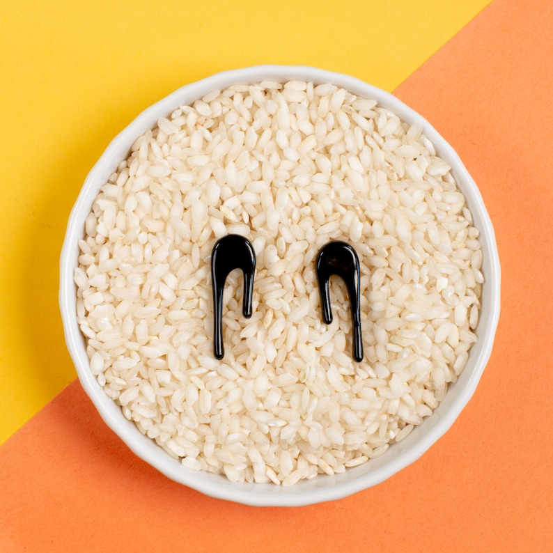Puede incluir: Un bol blanco lleno de arroz cocido con dos formas abstractas negras en la parte superior.