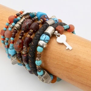 May include: A stack of colorful beaded bracelets with a silver key charm. The bracelets feature turquoise, brown, red, and orange beads.