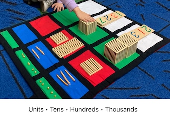 May include: A colourful educational mat with blocks and beads for learning maths concepts. The mat is divided into squares of red, green, blue, and white. Wooden blocks and number cards are placed on the mat. The text "Units • Tens • Hundreds • Thousands" is at the bottom.