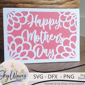 May include: White cardstock cut-out design with a pink background. The design features a floral border and the text "Happy Mother's Day".