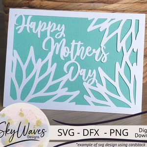 May include: A white card with a teal background and a cut-out design of leaves and the text "Happy Mother's Day". The card is on a wooden surface. The text "SVG - DFX - PNG Digital Download" is below the card.