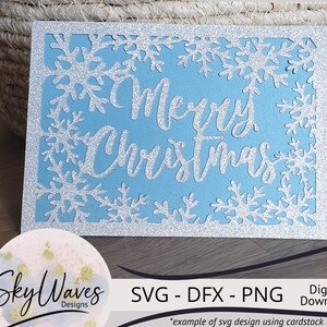 K&ouml;nnte beinhalten: Eine hellblaue Weihnachtskarte mit silbernem Glitzerrahmen und Schneeflocken-Ausschnitten. Die Worte "Merry Christmas" sind in silberner Schrift. Digitaler Download.
