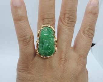 May include: A green jade ring with a carved design set in a gold band with small diamonds.