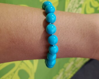 May include: A turquoise blue beaded bracelet with round beads.