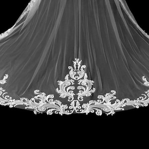 May include: A white wedding veil with an ornate, embroidered floral and scrollwork border. The veil is made of a sheer fabric, and the detailed edging adds a touch of elegance. The veil is against a black background.