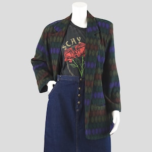 May include: A green, purple, and brown patterned blazer with a notched collar and flap pockets. The blazer is made of a soft, textured fabric.