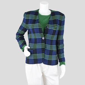 May include: A plaid blazer in navy, blue, and green, displayed on a mannequin. The blazer has a two-button closure and a notched lapel. The mannequin is also wearing a green sweater and white pants.
