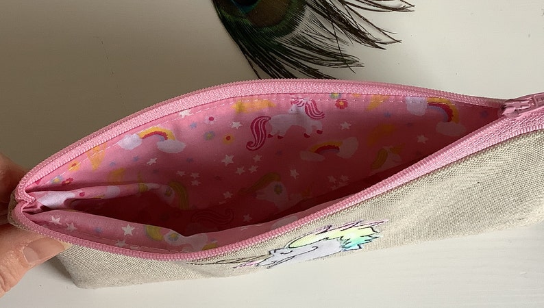 Unicorn motif personalised pencil case or cosmetic bag.  Pen or makeup pouch with choice of colour and coordinating lining.  Fastened with a zip and rainbow ribbon pull.  Ideal girls back to school gift