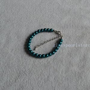 May include: A teal blue pearl bracelet with a silver clasp.