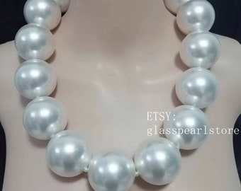 May include: A white pearl necklace with large, round pearls. The necklace is made of 12 pearls and is approximately 18 inches long.  Etsy: glasspearlstore