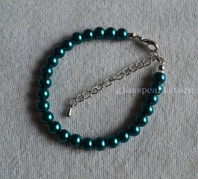 May include: A teal blue pearl bracelet with a silver clasp and extender chain.