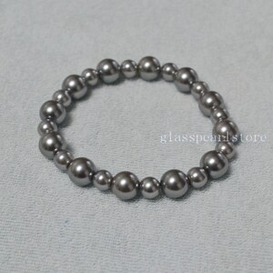 May include: A silver gray pearl bracelet with a total of 18 pearls.