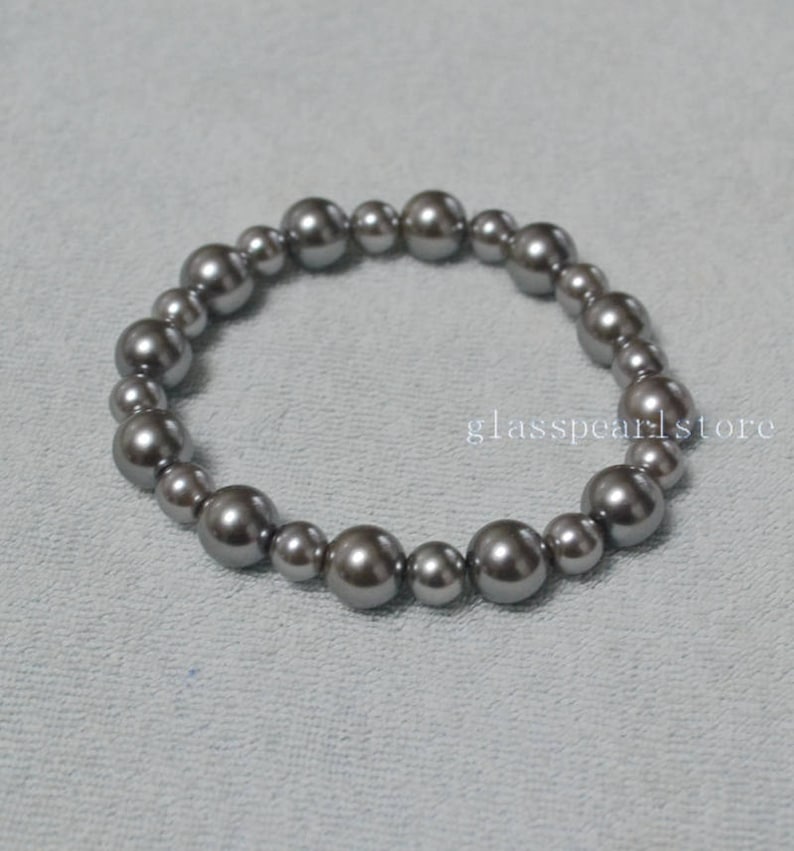 May include: A silver gray pearl bracelet with a total of 18 pearls.