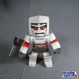 May include: A papercraft model of Megatron, a fictional character from the Transformers franchise. The model is made of white paper with red and black accents. Megatron has a large, square head with red eyes and a menacing expression. He is holding a large, black gun in his right hand.