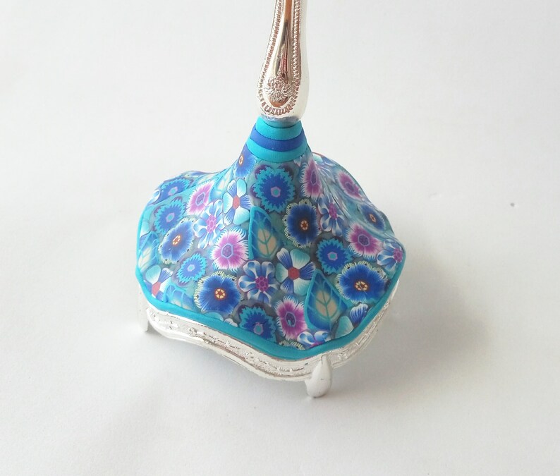 May include: A silver base with a blue and white floral design. The base has a decorative top with a silver stem.