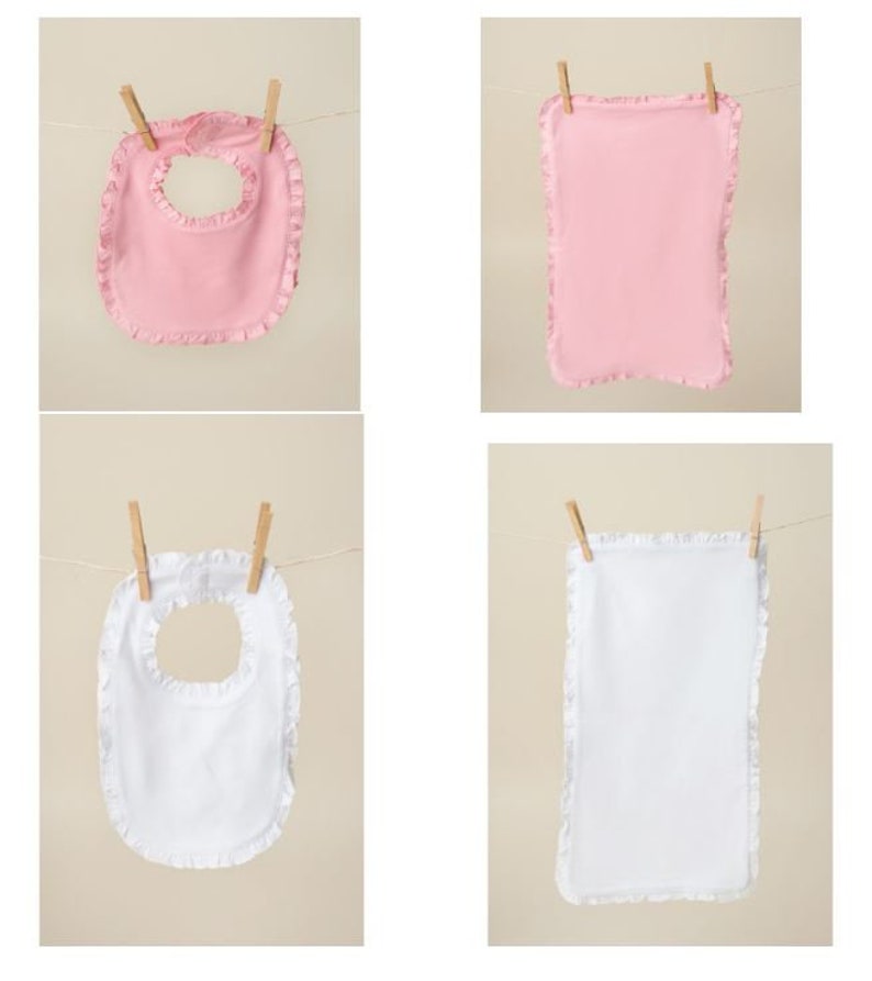 May include: Four baby bibs hanging on a clothesline. Two are pink with ruffled edges and two are white with ruffled edges.