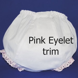 May include: White cotton baby bloomers with pink eyelet trim and a lace ruffle around the leg openings. "Pink Eyelet trim" is written on the bloomers.