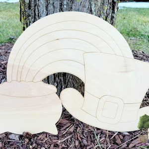 May include: Wooden cutout of a rainbow, pot of gold, and a leprechaun hat. The rainbow is arched over the pot of gold. The leprechaun hat is to the right of the pot of gold. All three are unfinished and ready to be painted.