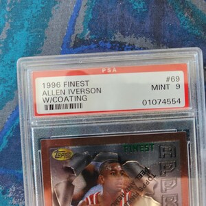 May include: A graded Allen Iverson 1996 Finest basketball card, encased in a protective holder. The card is graded MINT 9 by PSA, with the serial number 01074554. The card features Allen Iverson and the Topps Finest logo.