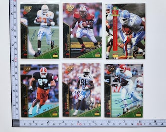 May include: A collection of six football trading cards featuring players in action. Each card has a player's image, signature, and team logo. The cards are on a green and gold background.