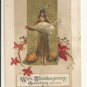 Puede incluir: Una postal antigua que muestra a una persona con un traje marrón con flecos y una pluma en el cabello, sosteniendo un pavo blanco grande. Dos calabazas naranjas están a sus pies sobre un fondo dorado texturizado, con hojas rojas y el texto With Thanksgiving Greeting.