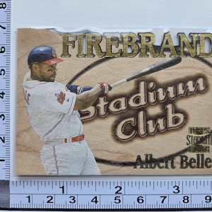 May include: A baseball card featuring Albert Belle in a white and red uniform, swinging a bat. The card has the text "FIREBRAND Stadium Club" and "Albert Belle" in a wooden-like design. The card measures approximately 3 inches by 4 inches.
