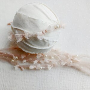 Puede incluir: Un conjunto de accesorios de fotograf&iacute;a para reci&eacute;n nacidos. Incluye un gorro blanco texturizado con una diadema de lazo rosa y una envoltura a juego. El conjunto est&aacute; adornado con perlas de imitaci&oacute;n, creando una est&eacute;tica suave y elegante.