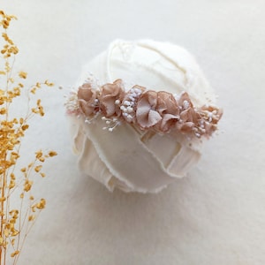 Könnte beinhalten: Ein weißes Stoffhaarband mit einem rosa Blütensaum. Das Haarband ist aus weichem, zartem Stoff gefertigt und perfekt für Neugeborenenfotografie.