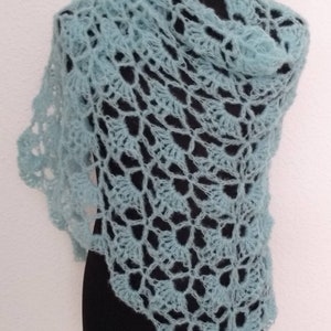 Könnte beinhalten: Ein hellblauer Häkel-Schal mit einem zarten Spitzenmuster. Der Schal ist über eine schwarze Schaufensterpuppe gelegt.