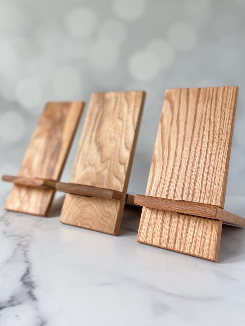 Set of natural Wooden cell phone stands on a white marble counter top showing the beautiful unique grain of each stand.