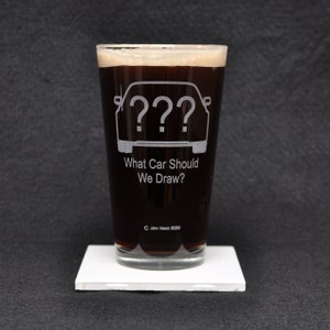 Peut inclure: Un verre à bière en verre transparent rempli d'un liquide brun foncé. Le verre présente un motif blanc d'une voiture avec des points d'interrogation à la place des phares et le texte "Quelle voiture devrions-nous dessiner ?"