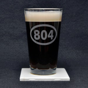 May include: A clear glass pint glass with a frosted oval design that says "804" on it. The glass is filled with a dark brown liquid.