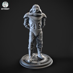 May include: A gray 3D printed figurine of a person wearing a futuristic suit with a helmet and a breathing apparatus. The figurine is standing on a round base with a textured surface.