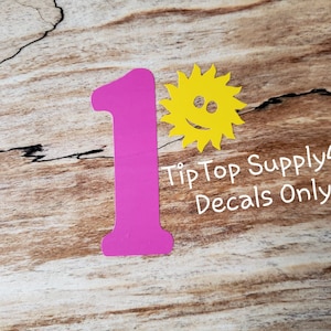 May include: Pink number one decal with a yellow smiling sun decal. Tip Top Supply4U Decals Only.