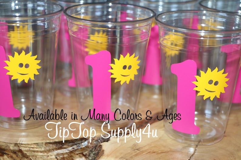 May include: Pink plastic cups with a yellow sun and the number one printed on them. The text "Available in Many Colors & Ages Tip Top Supply4u" is printed on the bottom of the cups.
