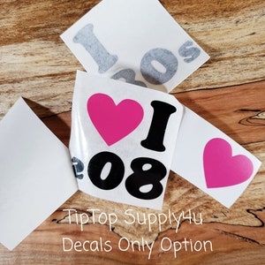 May include: White vinyl decals with the text "I 08" and a pink heart. The decals are shown on a wooden surface. The text "TipTop Supply4u Decals Only Option" is also visible.