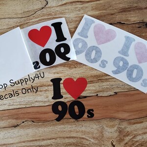 May include: A set of three vinyl decals featuring the text "I love the 90s" with a red heart. The decals are available in black and gray.